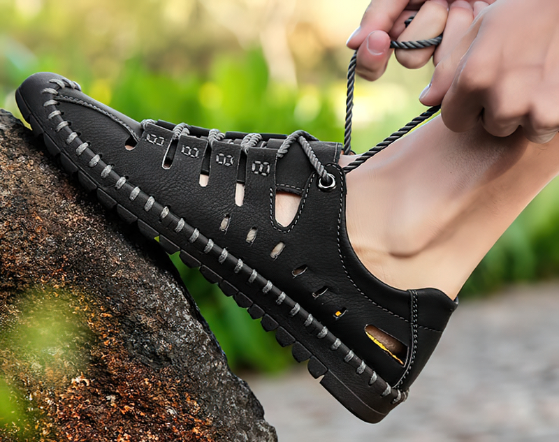 Men's lace-up leather soft sandal with durable rubber outsole, perfect for outdoor water activities, shown on rocky terrain.